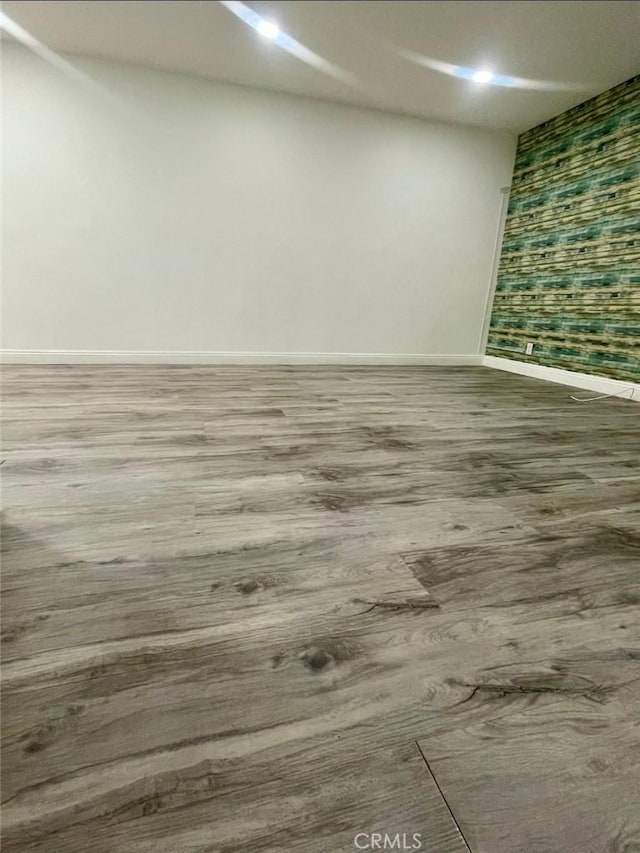 interior space with wallpapered walls, wood finished floors, and baseboards