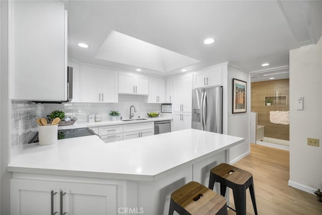 kitchen with a sink, recessed lighting, light countertops, and appliances with stainless steel finishes