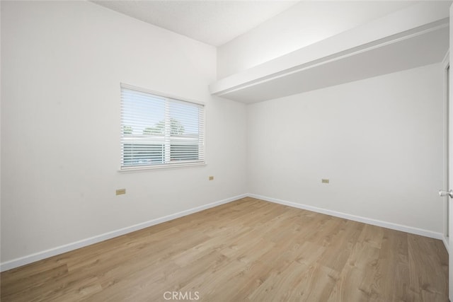 spare room featuring light wood-style flooring and baseboards