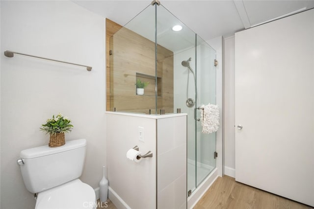bathroom featuring toilet, wood finished floors, a shower stall, and recessed lighting
