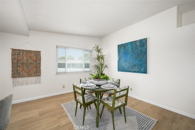 dining space with baseboards and wood finished floors