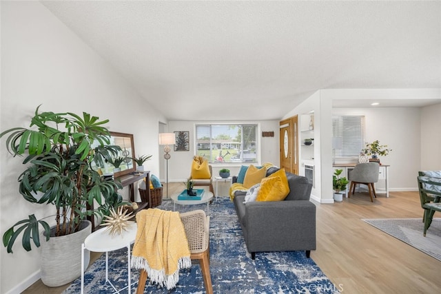 living room featuring vaulted ceiling, wood finished floors, and baseboards