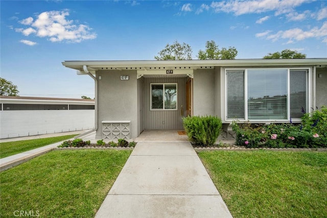 entrance to property featuring a yard and stucco siding