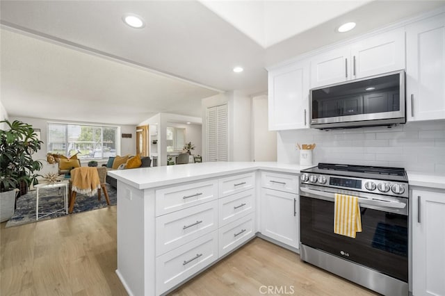 kitchen featuring a peninsula, white cabinetry, light wood-type flooring, light countertops, and appliances with stainless steel finishes