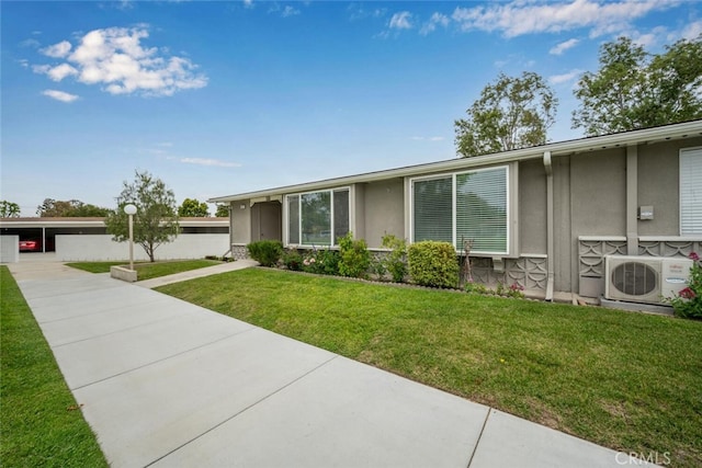 view of front facade featuring stucco siding, ac unit, and a front yard