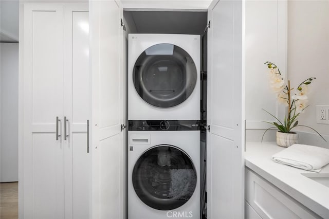 washroom featuring laundry area, stacked washer / dryer, and wood finished floors