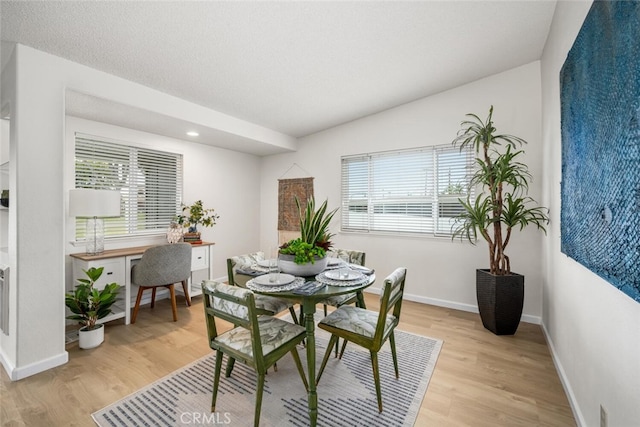 dining space with baseboards and light wood-style flooring