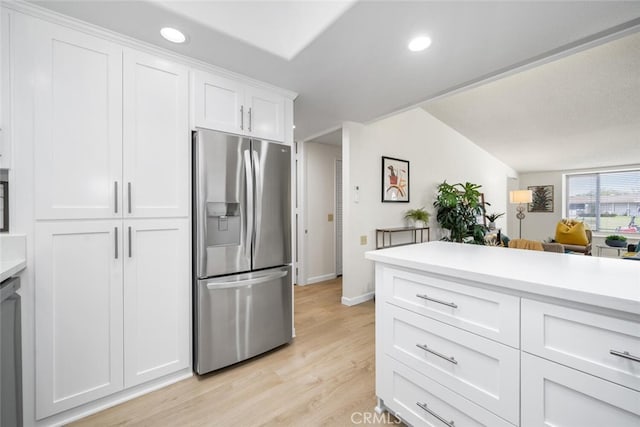 kitchen featuring light wood-type flooring, white cabinetry, stainless steel fridge, light countertops, and baseboards