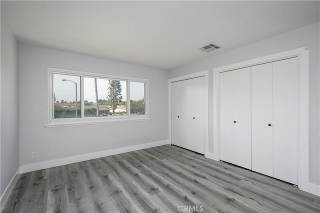 3500 W Manchester Blvd Unit 15, Inglewood, CA 90305 - unfurnished bedroom featuring baseboards, visible vents, two closets, and wood finished floors