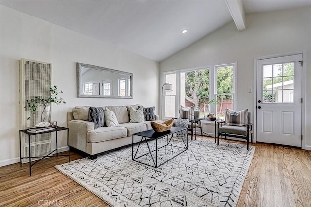 living area featuring wood finished floors, a wealth of natural light, a heating unit, and beam ceiling