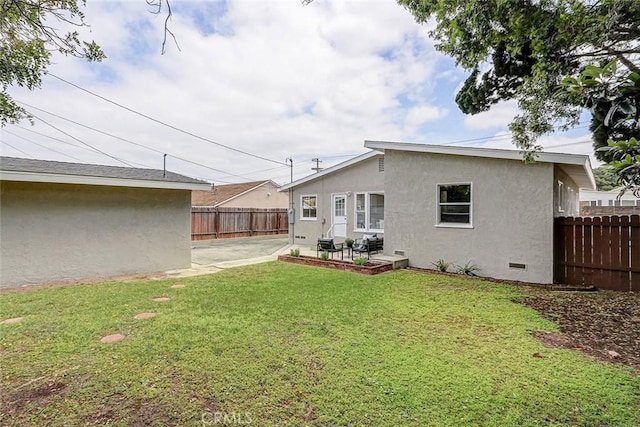 back of property with a yard, fence, a patio, stucco siding, and crawl space