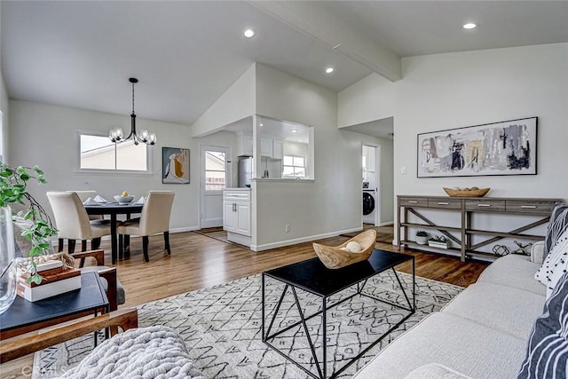 living room featuring washer / clothes dryer, lofted ceiling with beams, a notable chandelier, and wood finished floors