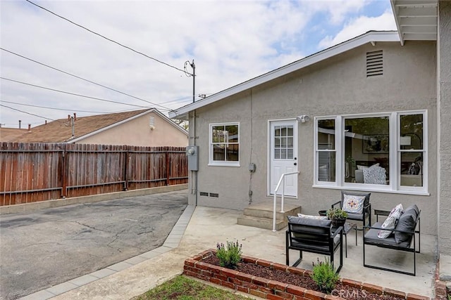back of property featuring stucco siding, crawl space, fence, and a patio area