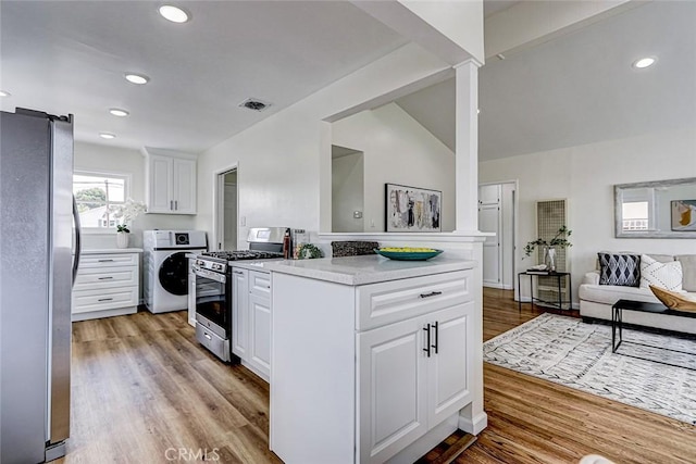 kitchen featuring washer / dryer, light countertops, appliances with stainless steel finishes, and white cabinets