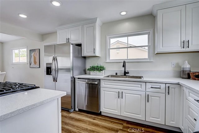 kitchen featuring wood finished floors, a sink, white cabinetry, appliances with stainless steel finishes, and recessed lighting