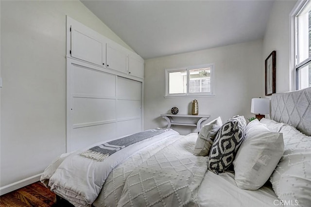 bedroom with lofted ceiling, baseboards, a closet, and wood finished floors