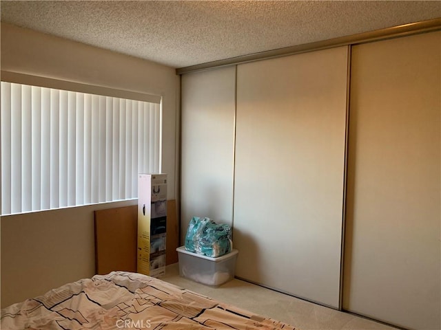 bedroom with a closet, a textured ceiling, and carpet floors