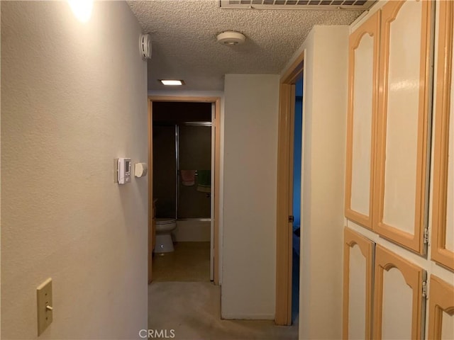 corridor with carpet, a textured ceiling, and visible vents
