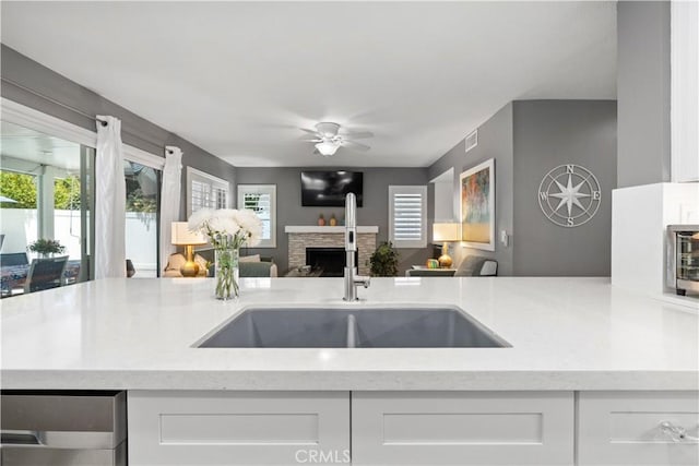 30151 Via Amante, Menifee, CA 92584 - kitchen with a sink, open floor plan, a fireplace, a ceiling fan, and white cabinets