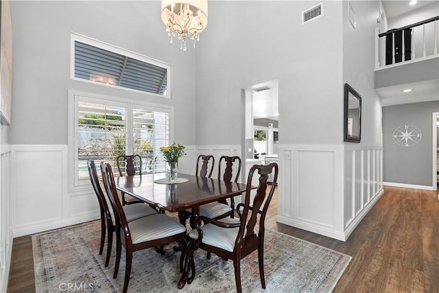30151 Via Amante, Menifee, CA 92584 - dining area featuring a towering ceiling, wood finished floors, wainscoting, a chandelier, and a decorative wall