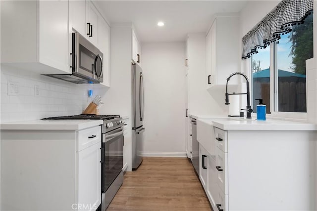 17730 Regency Cir, Bellflower, CA 90706 - kitchen with stainless steel appliances, recessed lighting, light wood-style flooring, white cabinetry, and decorative backsplash