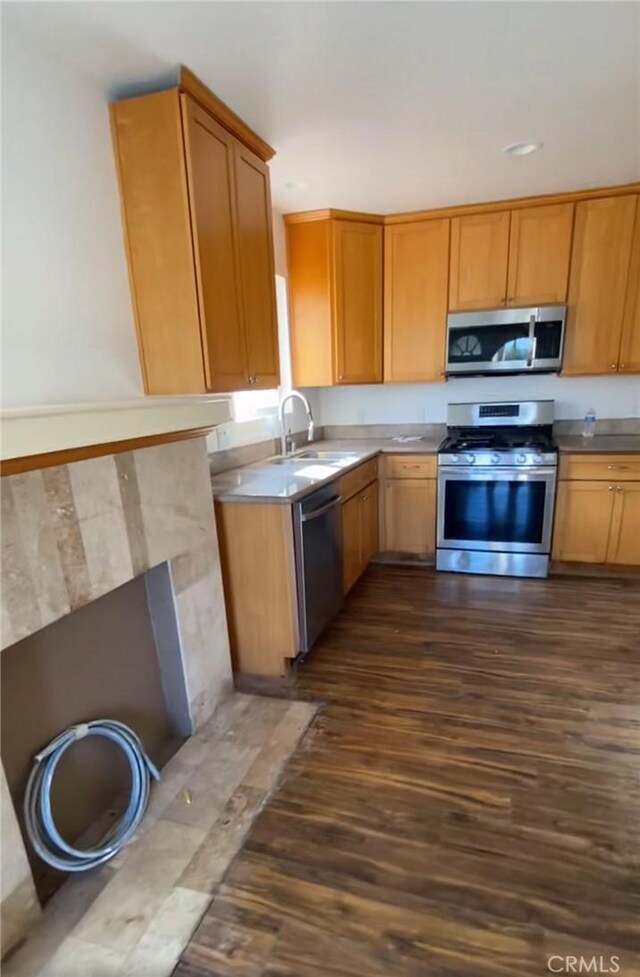 5507 S Manhattan Pl, Los Angeles, CA 90062 - kitchen featuring stainless steel appliances, a sink, dark wood-type flooring, brown cabinets, and light countertops