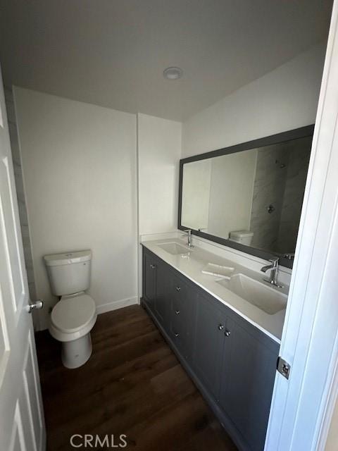 5507 S Manhattan Pl, Los Angeles, CA 90062 - bathroom with toilet, double vanity, a sink, and wood finished floors