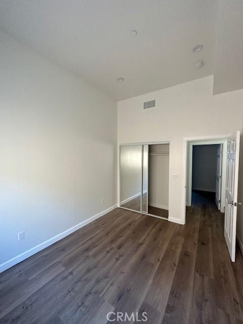 5507 S Manhattan Pl, Los Angeles, CA 90062 - unfurnished bedroom with baseboards, a closet, dark wood finished floors, and visible vents