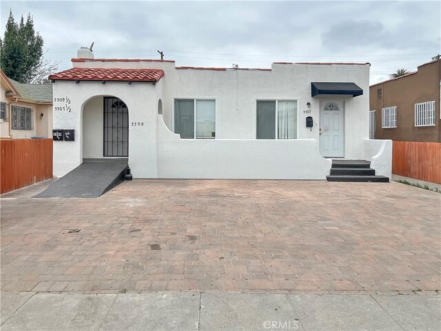 5507 S Manhattan Pl, Los Angeles, CA 90062 - mediterranean / spanish-style home featuring stucco siding, a tiled roof, and fence