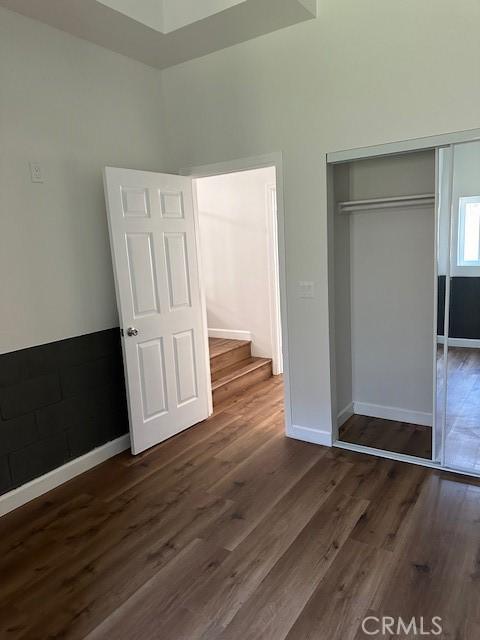 5507 S Manhattan Pl, Los Angeles, CA 90062 - unfurnished bedroom featuring baseboards, a closet, and dark wood-type flooring
