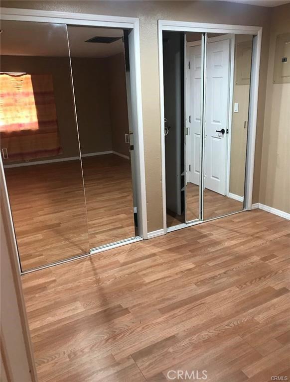 2517 E Walnut Crk, West Covina, CA 91791 - unfurnished bedroom with two closets, wood finished floors, and baseboards