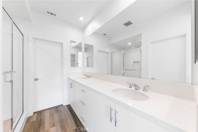 full bath featuring a sink, a stall shower, visible vents, and wood finished floors