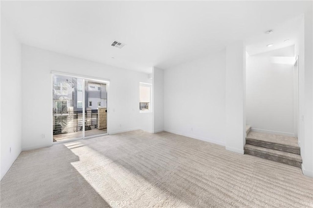 unfurnished living room with carpet, visible vents, and baseboards