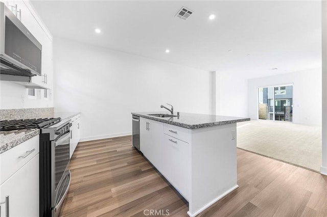 kitchen with stainless steel appliances, visible vents, a sink, and light stone countertops