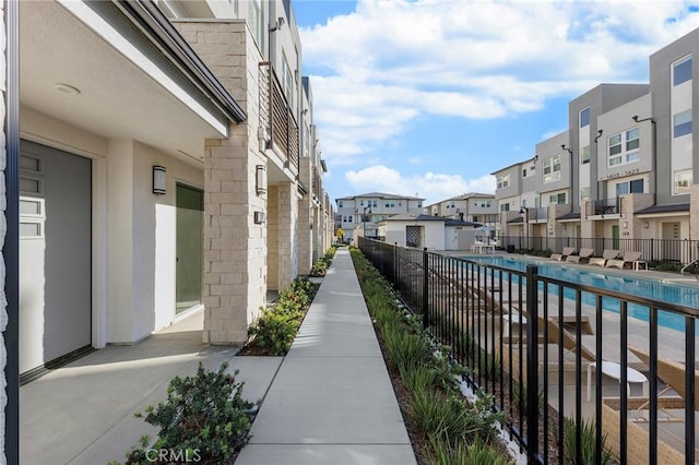 view of community featuring a swimming pool, a residential view, and fence