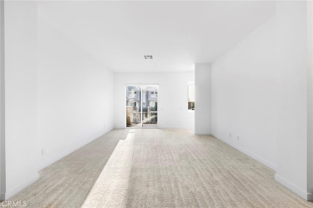spare room featuring light colored carpet and visible vents