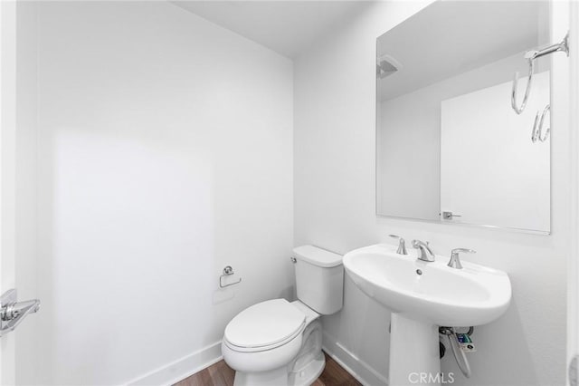 bathroom with toilet, baseboards, and wood finished floors