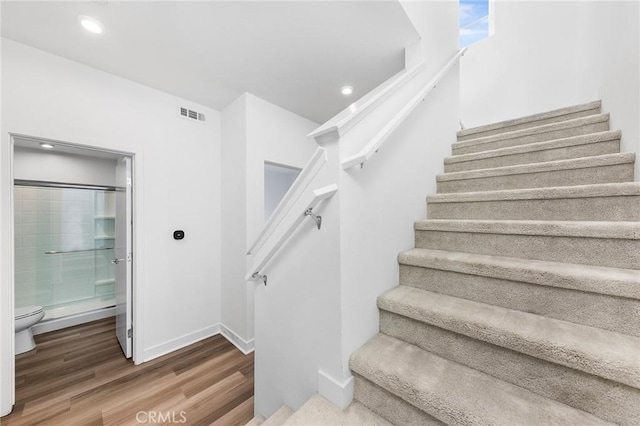 stairs with visible vents, wood finished floors, baseboards, and recessed lighting