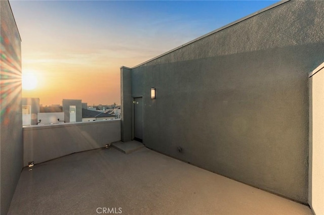 property exterior at dusk with stucco siding and a balcony
