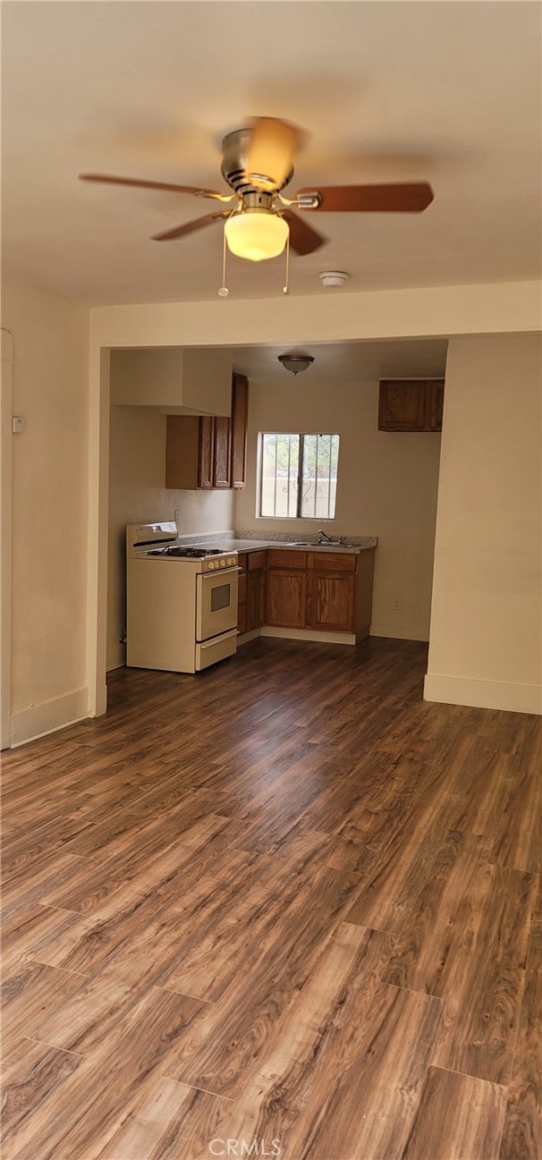 954 N Van Ness Ave, Los Angeles, CA 90038 - unfurnished living room featuring dark wood finished floors, baseboards, and ceiling fan