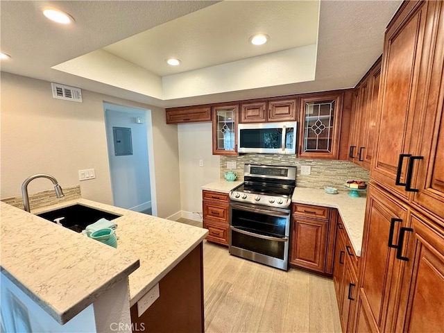 9556 Bloomfield St, Cypress, CA 90630 - kitchen with stainless steel appliances, a sink, light wood-type flooring, a raised ceiling, and brown cabinets