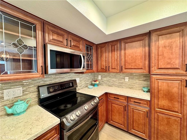 9556 Bloomfield St, Cypress, CA 90630 - kitchen with appliances with stainless steel finishes, tasteful backsplash, light stone counters, and glass insert cabinets