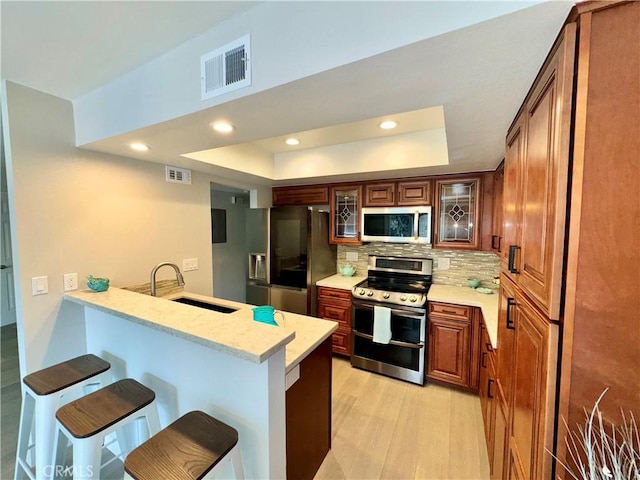 9556 Bloomfield St, Cypress, CA 90630 - kitchen with stainless steel appliances, a sink, a tray ceiling, a breakfast bar, and a peninsula