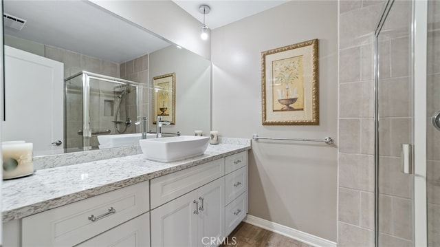 bathroom with a shower stall, vanity, wood finished floors, and baseboards
