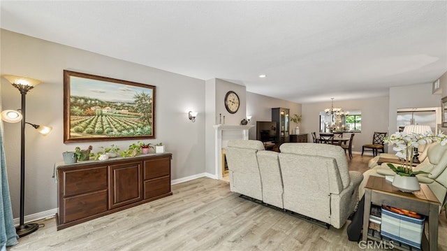 living area with a chandelier, light wood-style floors, baseboards, and recessed lighting