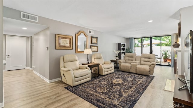 living area featuring baseboards, light wood-type flooring, and recessed lighting