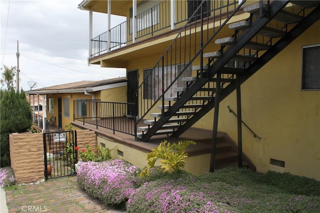view of home's exterior with stairway, a balcony, stucco siding, and crawl space