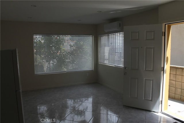 empty room featuring baseboards, tile patterned floors, and a wall mounted air conditioner