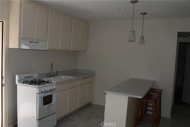 kitchen with a peninsula, a kitchen bar, white gas stove, a sink, and under cabinet range hood