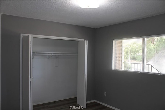 unfurnished bedroom featuring dark wood-style floors, a closet, and a textured ceiling